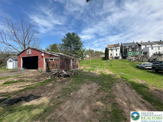 view of yard featuring dirt driveway, an outbuilding, and a detached garage