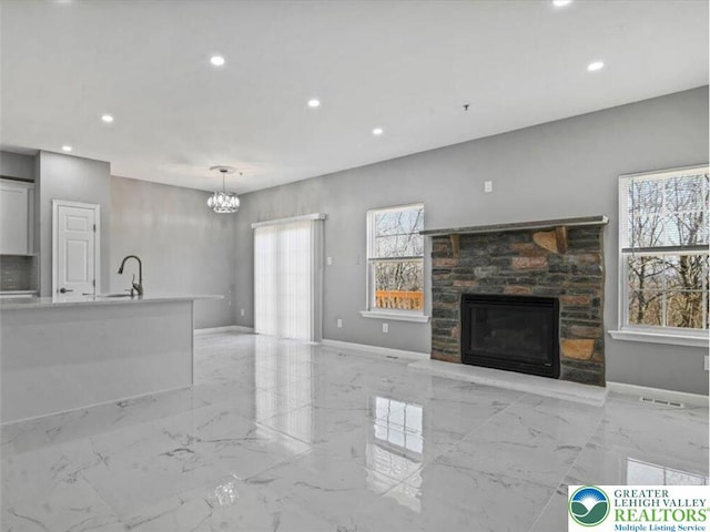 unfurnished living room with marble finish floor, a fireplace, recessed lighting, and a chandelier
