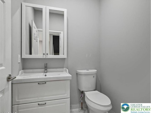 half bath with vanity, baseboards, and toilet