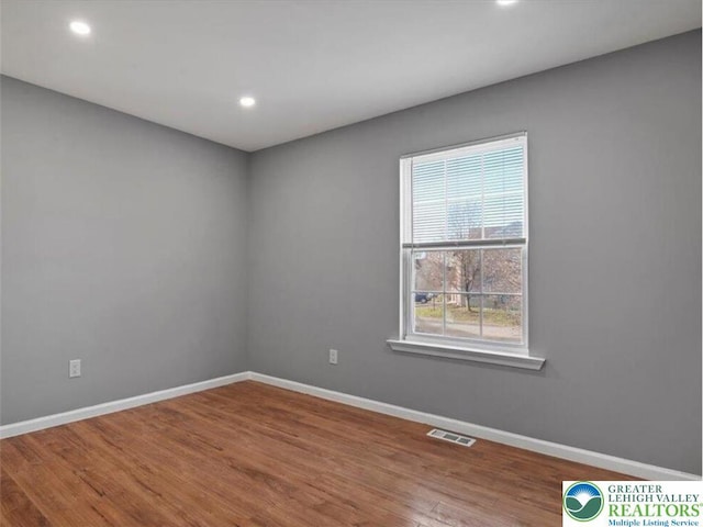 empty room featuring recessed lighting, baseboards, visible vents, and wood finished floors