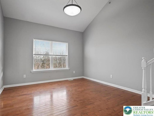 spare room featuring baseboards, lofted ceiling, and wood finished floors