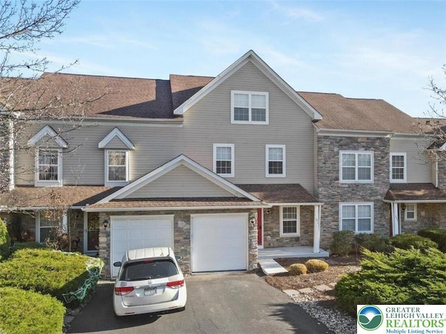 view of front of property featuring driveway, a shingled roof, and stone siding