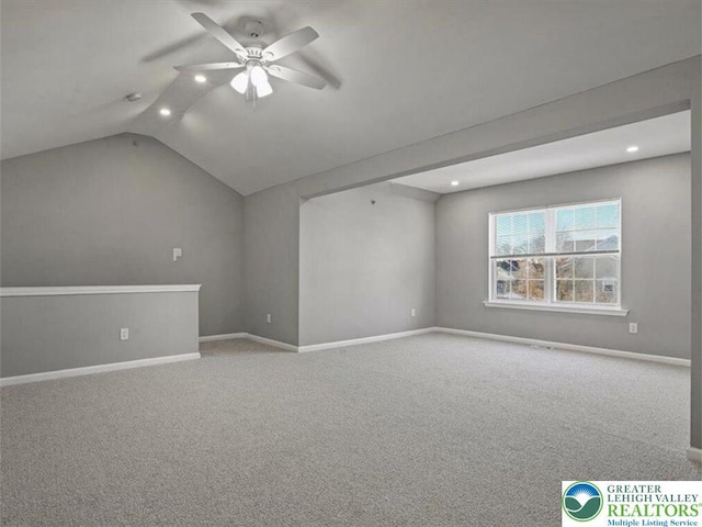 empty room featuring carpet flooring, ceiling fan, baseboards, and lofted ceiling