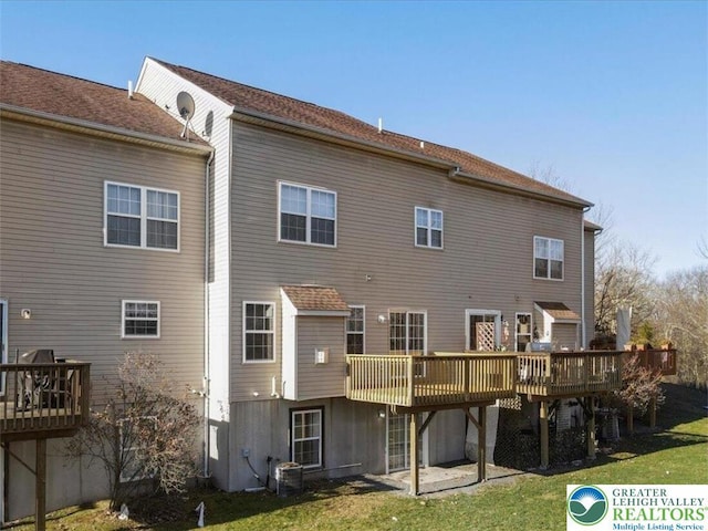 back of house featuring a lawn and a wooden deck