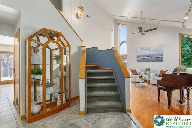 staircase with track lighting, baseboards, a ceiling fan, and visible vents