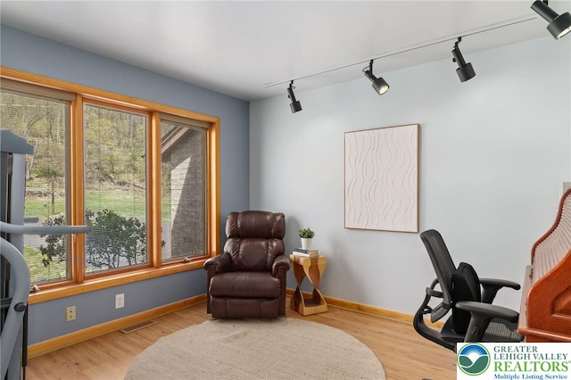 living area featuring baseboards, visible vents, track lighting, and wood finished floors