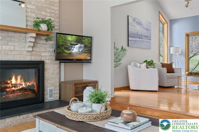 living room featuring visible vents, baseboards, wood finished floors, and a fireplace