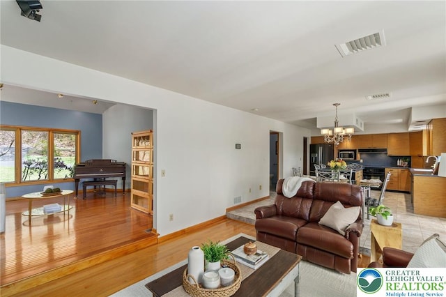 living area with a chandelier, visible vents, and light wood-style floors