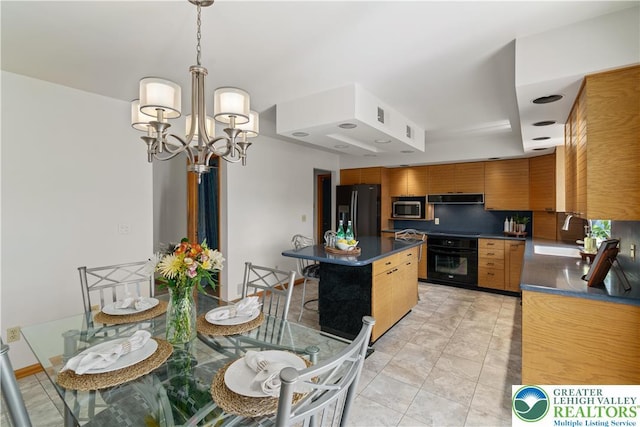 kitchen with dark countertops, ventilation hood, a chandelier, a sink, and black appliances