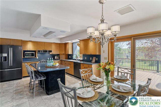 kitchen with an inviting chandelier, black fridge, a sink, dishwasher, and visible vents