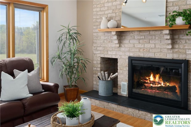 interior space featuring visible vents, a brick fireplace, and wood finished floors