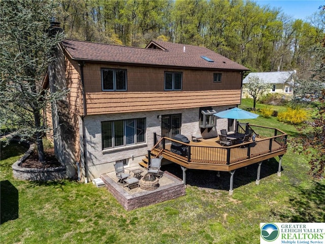 back of house featuring a wooden deck, a chimney, a shingled roof, a patio area, and a lawn