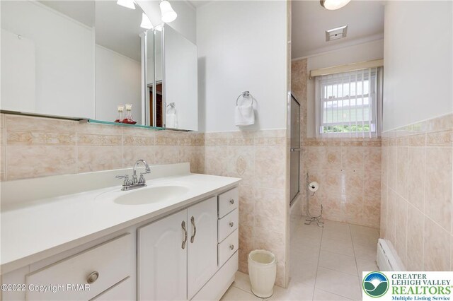 full bathroom with visible vents, vanity, tile patterned flooring, tile walls, and enclosed tub / shower combo