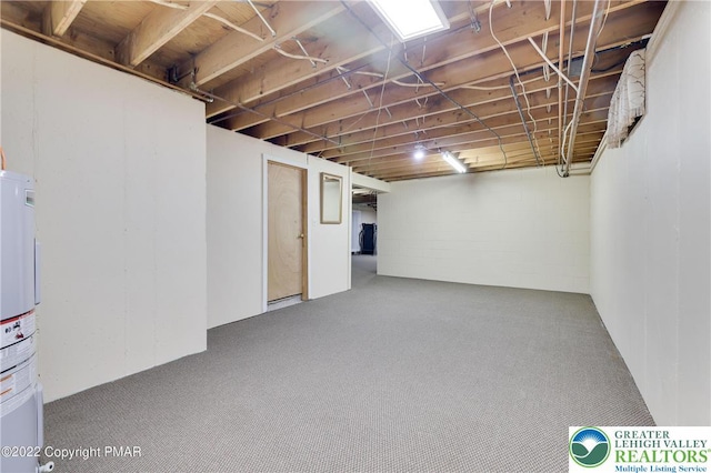 below grade area with carpet flooring, concrete block wall, and water heater