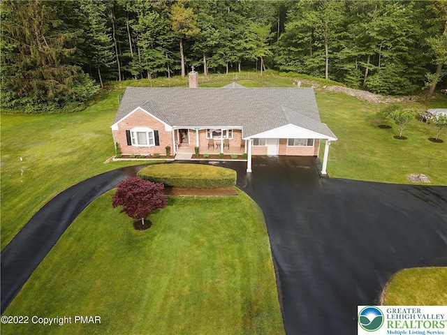 view of front of house featuring a porch, a chimney, a front yard, a carport, and aphalt driveway