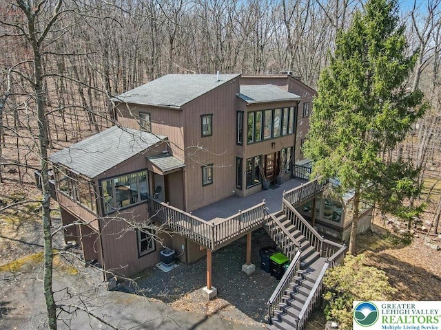 back of property with stairway, a deck, and a shingled roof