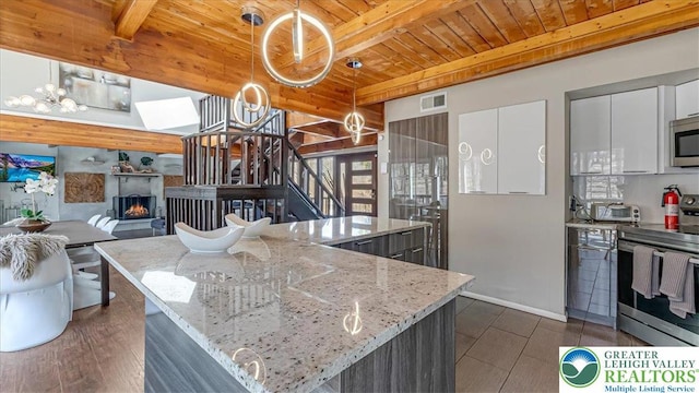 kitchen with appliances with stainless steel finishes, wooden ceiling, beam ceiling, and visible vents