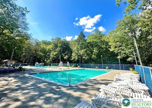pool with a patio area and fence