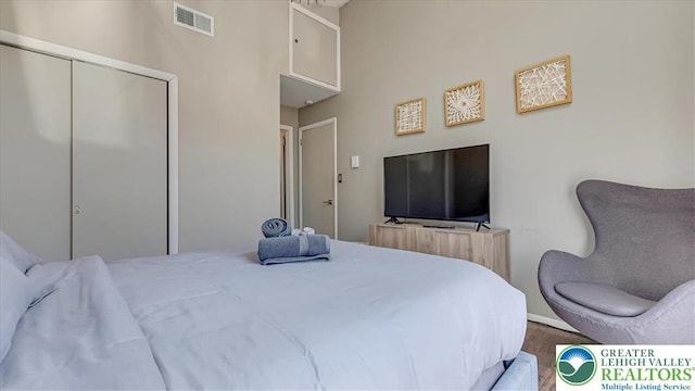 bedroom featuring visible vents, baseboards, wood finished floors, and a closet
