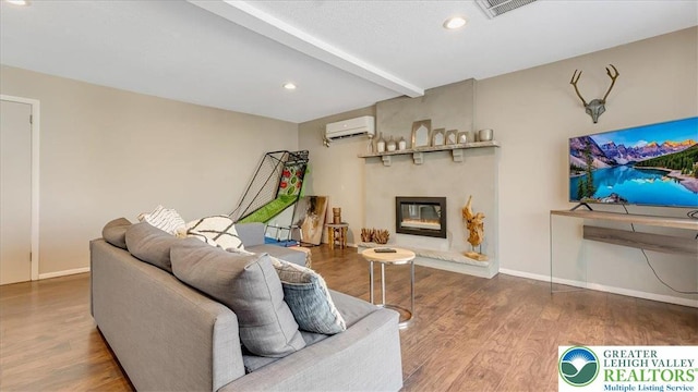 living area with visible vents, a wall mounted AC, beam ceiling, wood finished floors, and baseboards