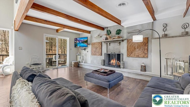 living area featuring visible vents, beam ceiling, and wood finished floors