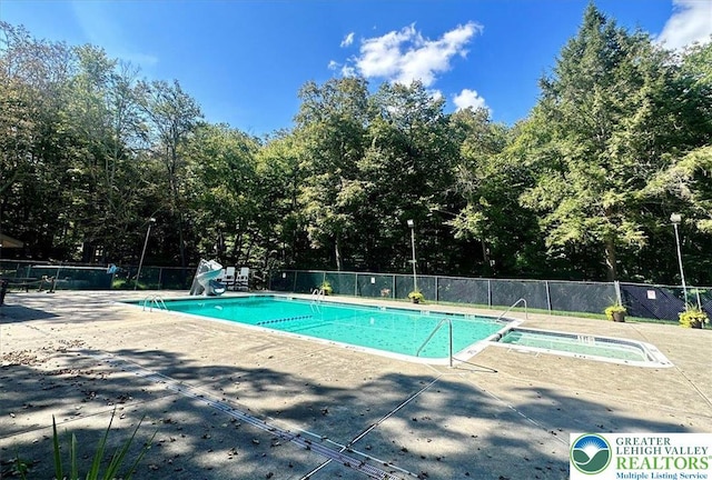 community pool featuring a community hot tub, a patio area, and fence