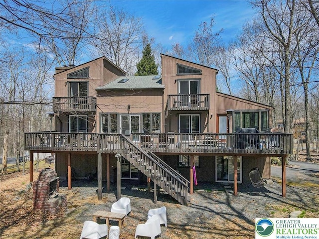 rear view of property featuring stairs, a balcony, and a deck