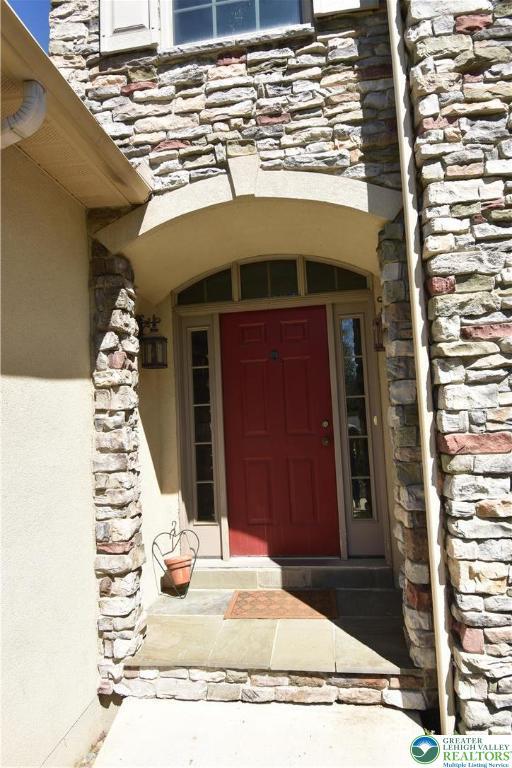 doorway to property featuring stone siding and stucco siding