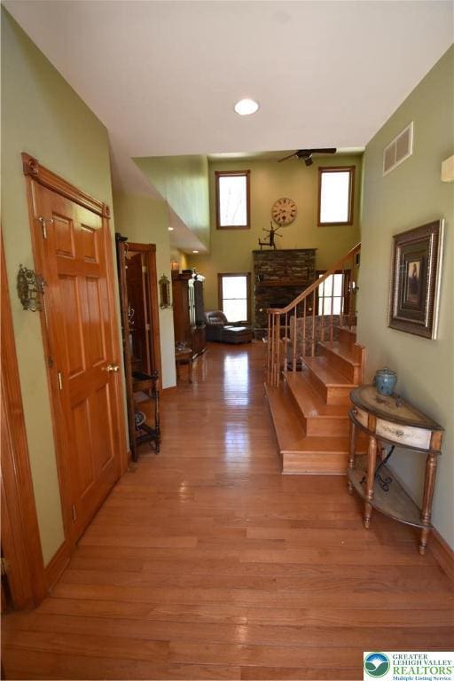 corridor featuring stairway, a wealth of natural light, light wood-style flooring, and visible vents