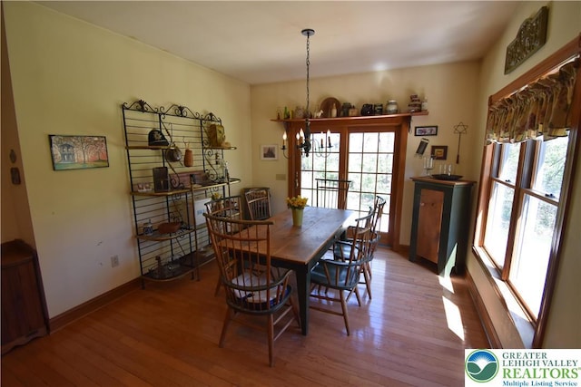 dining room featuring baseboards, hardwood / wood-style flooring, and a chandelier