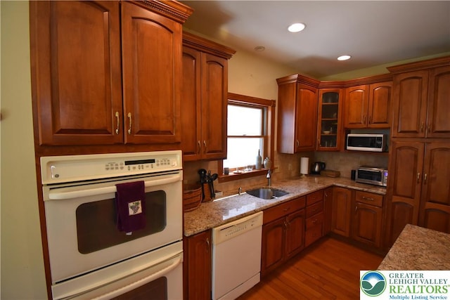 kitchen featuring light stone counters, a sink, light wood-style floors, white appliances, and recessed lighting