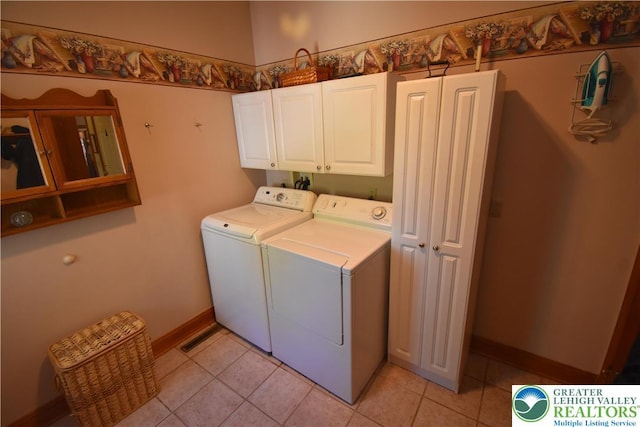 laundry room with cabinet space, light tile patterned floors, baseboards, and washer and clothes dryer