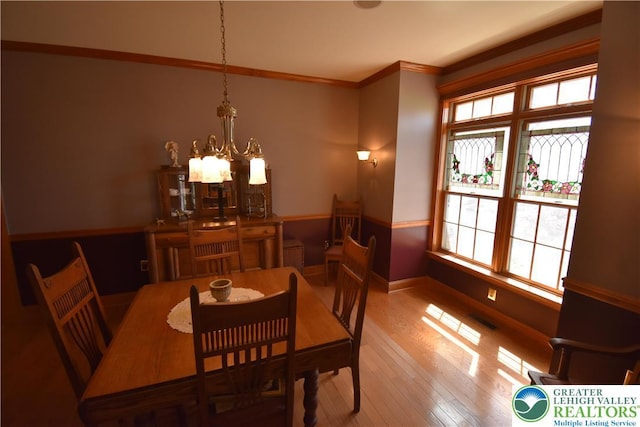 dining area with an inviting chandelier, crown molding, a wealth of natural light, and hardwood / wood-style floors
