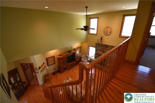staircase with baseboards, a ceiling fan, wood finished floors, and a fireplace