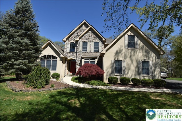 traditional home featuring stone siding, a front yard, and stucco siding