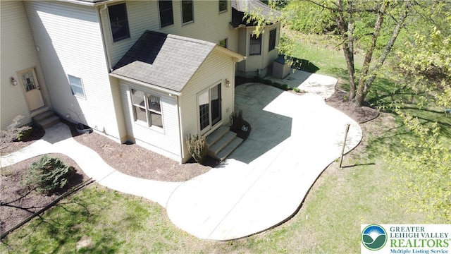 view of property exterior with roof with shingles, a patio, and entry steps