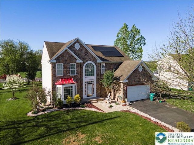 view of front of property with a front yard, driveway, solar panels, and stone siding