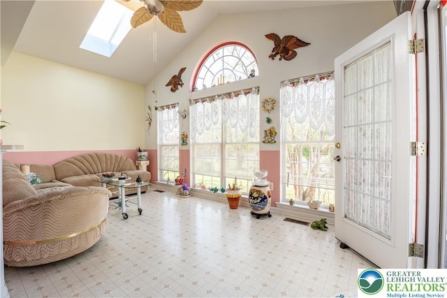 interior space with visible vents, ceiling fan, a skylight, and high vaulted ceiling