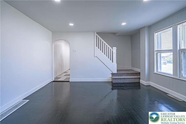 unfurnished living room featuring visible vents, stairs, wood finished floors, recessed lighting, and arched walkways