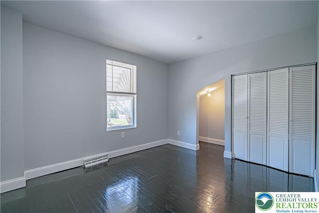 unfurnished bedroom with visible vents, wood-type flooring, baseboards, and a closet