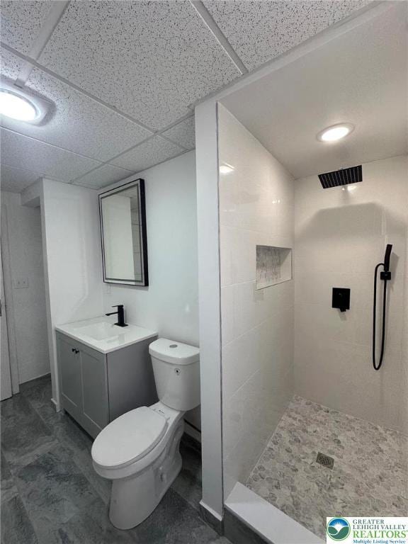 bathroom featuring toilet, visible vents, tiled shower, and vanity