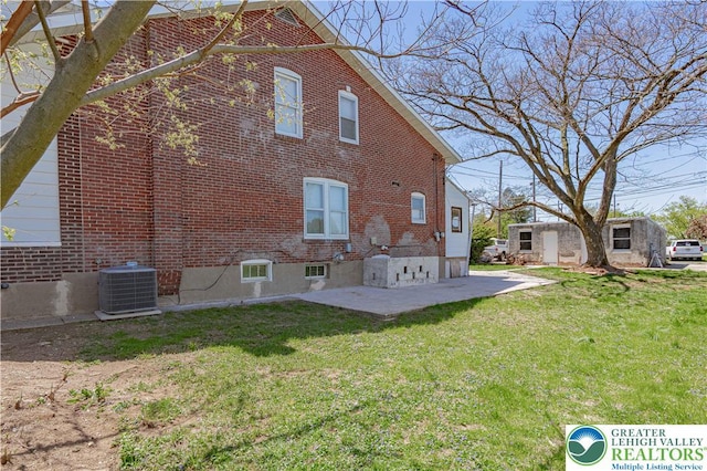 back of house featuring brick siding, central AC unit, a yard, and a patio