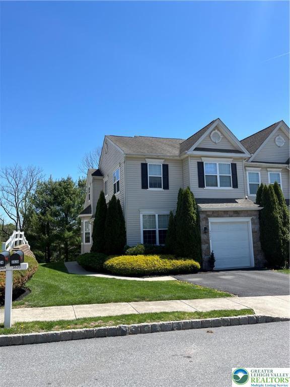 view of front facade with a garage, a front yard, and aphalt driveway