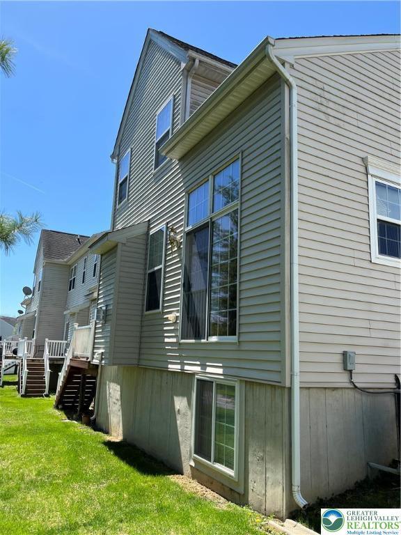 view of side of property featuring a lawn, a deck, and stairway