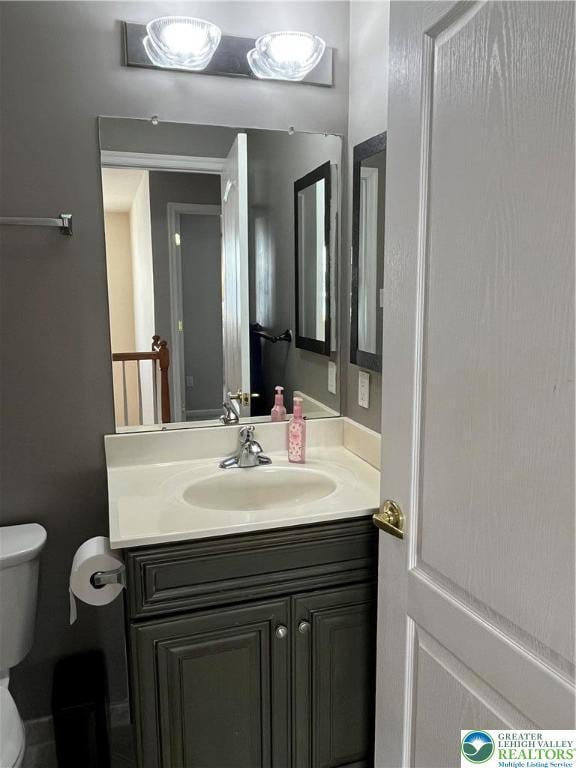 half bathroom with vanity and toilet