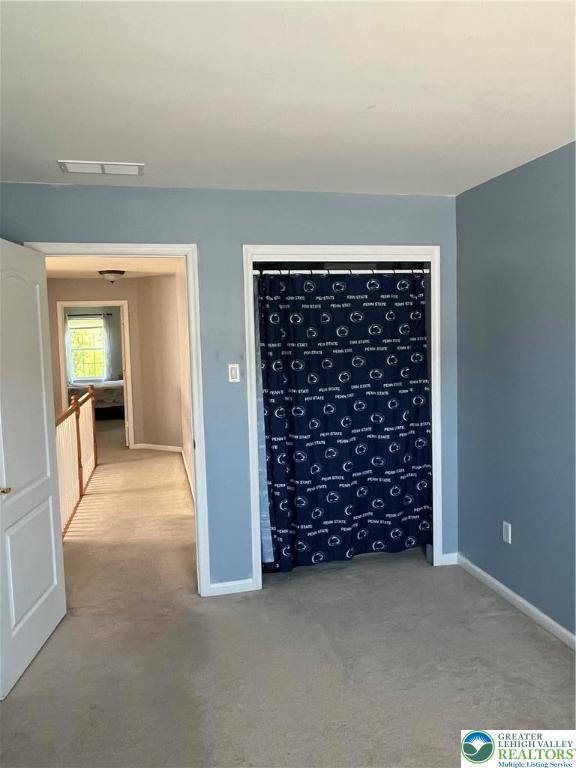 carpeted spare room featuring baseboards and visible vents