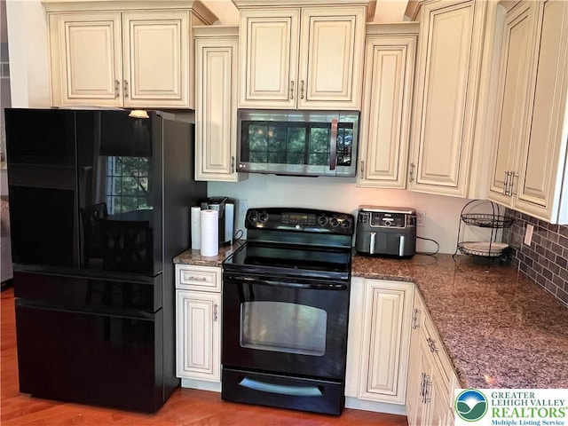 kitchen with tasteful backsplash, black appliances, and cream cabinetry
