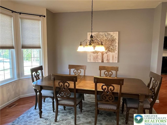 dining area with an inviting chandelier, baseboards, wood finished floors, and visible vents
