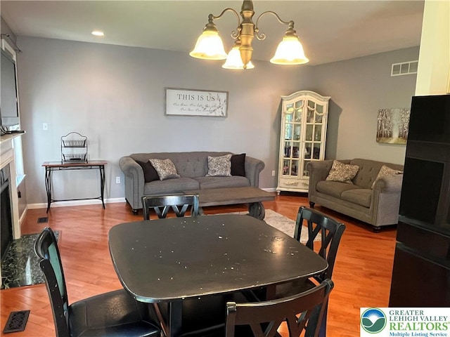 dining room featuring an inviting chandelier, a fireplace, recessed lighting, wood finished floors, and visible vents