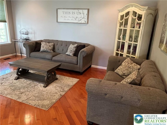 living room featuring baseboards, wood finished floors, and visible vents